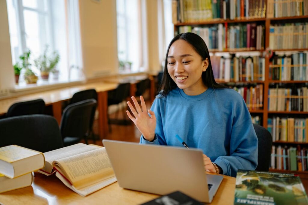 A Woman in a Blue Sweater Typing on a Laptop